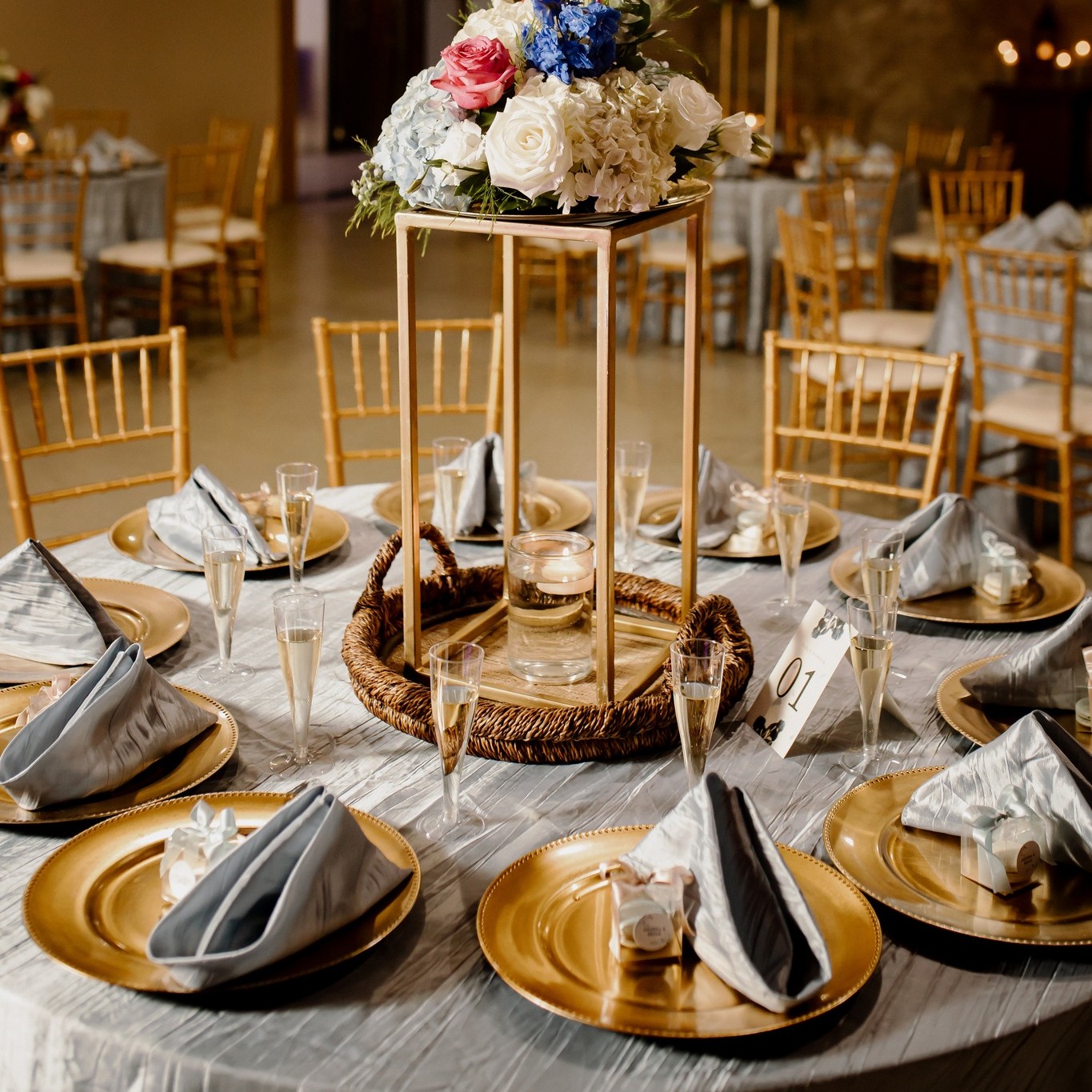 Decoración de mesa de boda con platos dorados y arreglos florales elegantes